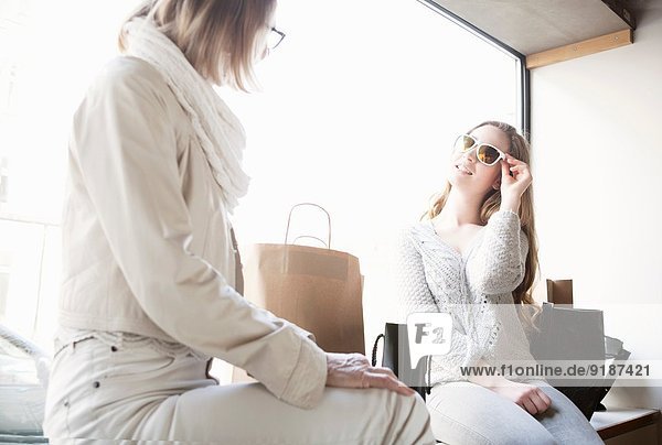 Seniorin und Enkelin beim Anprobieren der Sonnenbrille im Laden