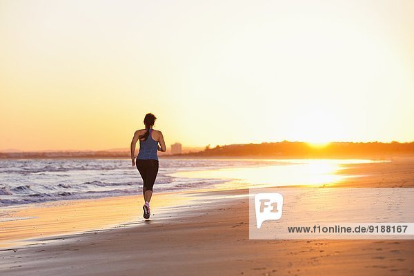 Frau Strand Sonnenuntergang rennen