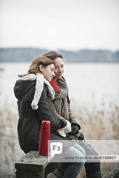 Mother and teenage daughter sitting on bench