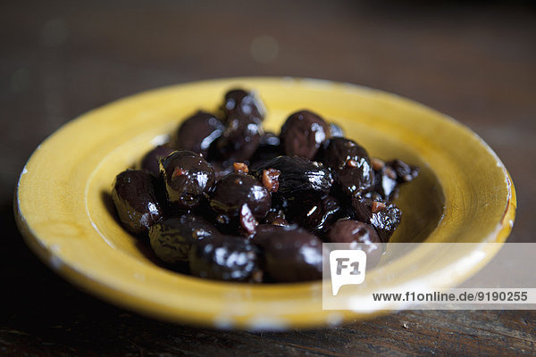 Nahaufnahme von marinierten schwarzen Oliven im Teller