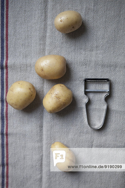 Directly above shot of potatoes and peeler on napkin
