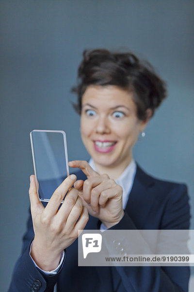 Überraschte Geschäftsfrau mit Blank Futuristic Transparent Mobile
