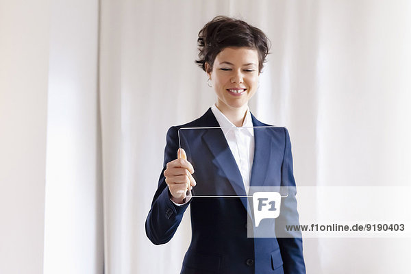 Glückliche  attraktive Geschäftsfrau  die auf ein leeres  transparentes digitales Tablett schaut.