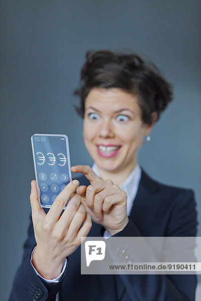 Überraschte Geschäftsfrau mit futuristischem Transparent Mobile mit Eurozeichen