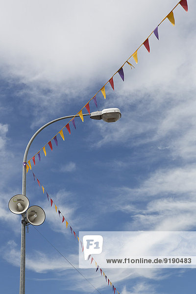 Flaggen- und Straßenbeleuchtung mit Lautsprechern gegen bewölkten Himmel
