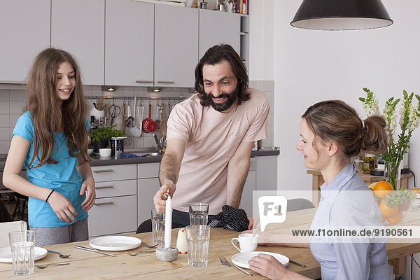Lächelnde Familie arrangiert Esstisch in der Küche