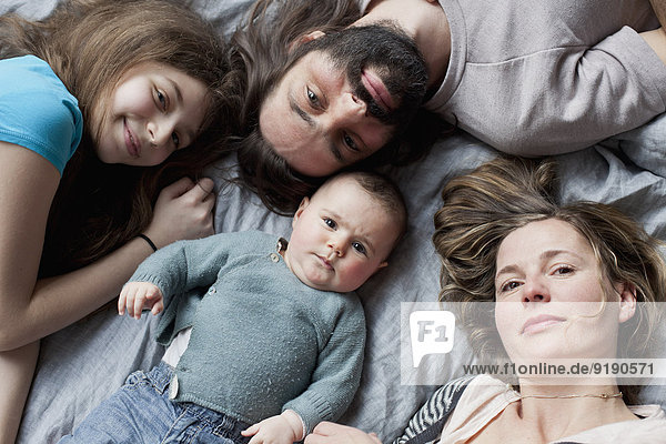 Hochwinkliges Porträt einer Familie  die sich auf dem Bett ausruht