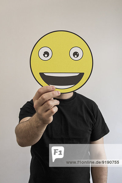 Mann mit einem wirklich glücklichen Emoticon-Gesicht vor dem Gesicht