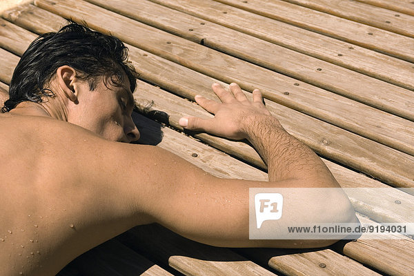 Mann beim Sonnenbaden auf dem Holzdeck