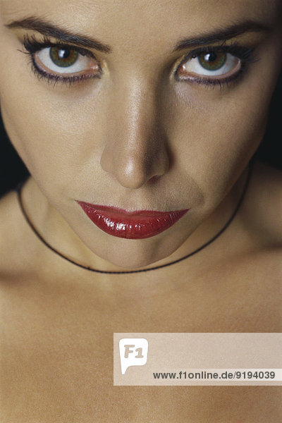 Frau in schwerem Make-up starrt in die Kamera.