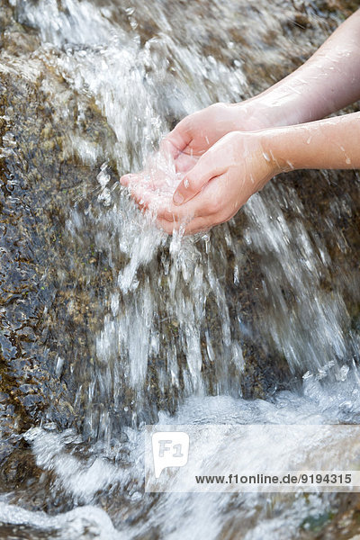 Kind hält schalenförmige Hände unter frischem  fließendem Wasser  abgeschnitten