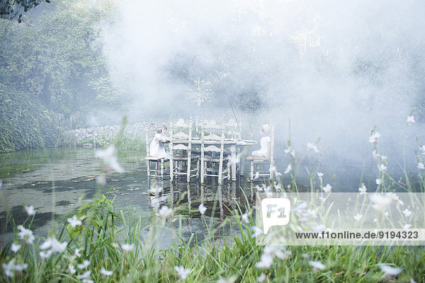 Kinder sitzen am Esstisch auf einem Teich  umgeben von Rauch.