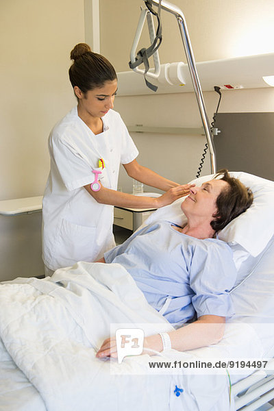 Krankenschwester  die die Patientin auf dem Krankenhausbett behandelt