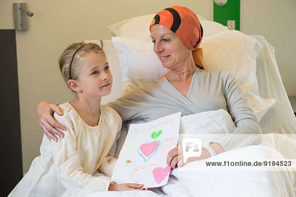 Girl giving greeting card to her illness mother