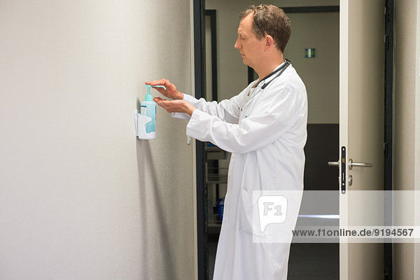 Male doctor using hygiene hand wash in hospital room