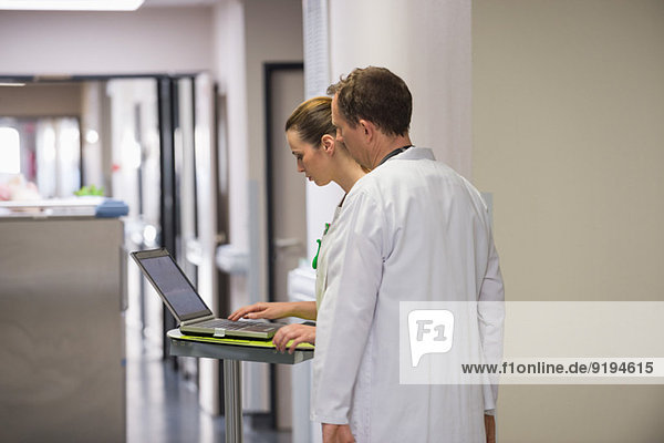 Doctor and female nurse analyzing medical report on a laptop in a hospital