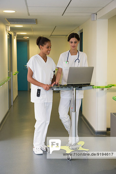 Ärztin und Krankenschwester mit Laptop im Krankenhausflur