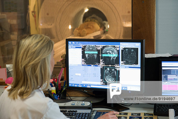Female doctor examining brain MRI scan on computer