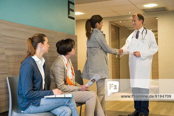 Male doctor shaking hands with his patient in waiting room