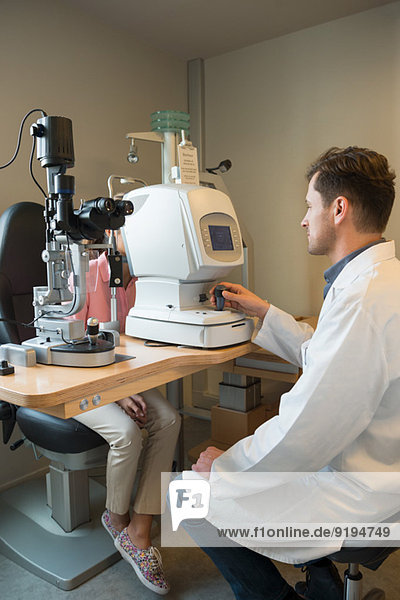 Male optometrist examining woman's eyes