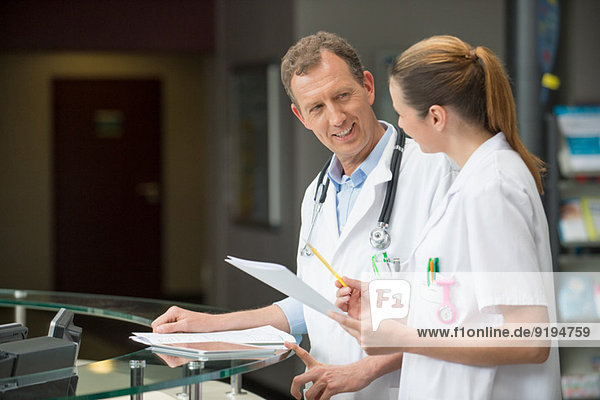 Two doctors discussing at hospital reception desk