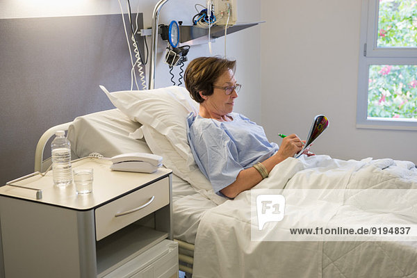 Woman writing on hospital bed