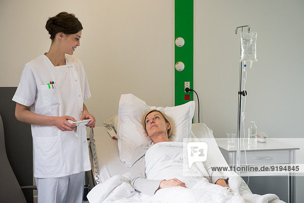 Medical attendant examining a female patient in hospital bed