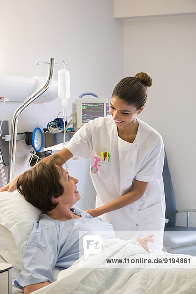 Krankenschwester assistiert Patientin auf Krankenhausbett