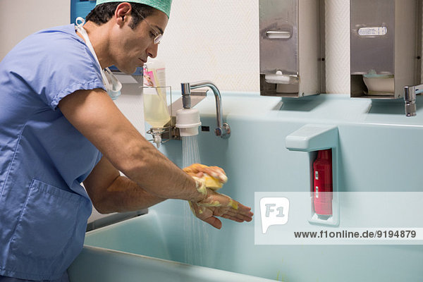 Male surgeon washing hands with disinfectant betadine in operating room