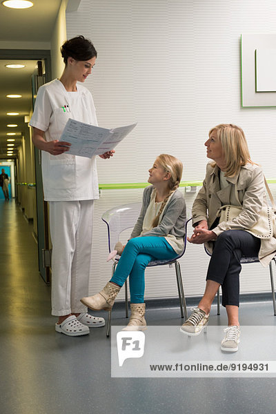 Krankenschwester diskutiert Bericht mit Patienten im Wartezimmer