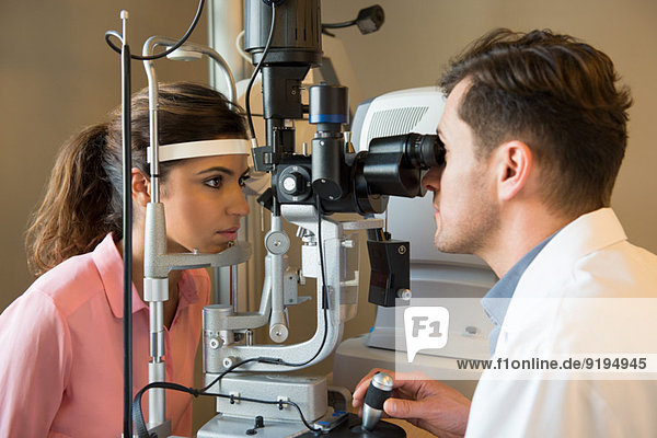 Male optometrist examining woman's eyes