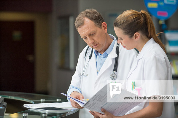 Two doctors discussing medical report at hospital reception desk