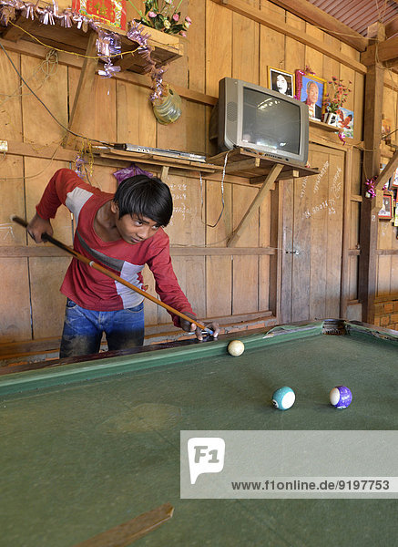 Cambodian youth playing pool billiards in a simple wooden hut  Banlung  Ratanakiri Province  Cambodia
