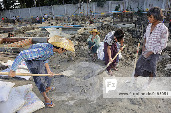 Children and teenagers mix concrete on a high rise construction site  Mandalay  Myanmar