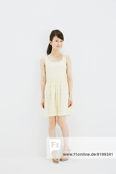 Japanese young woman in a one piece dress standing against white background