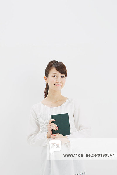 Japanese young woman in a white shirt with a book against white background