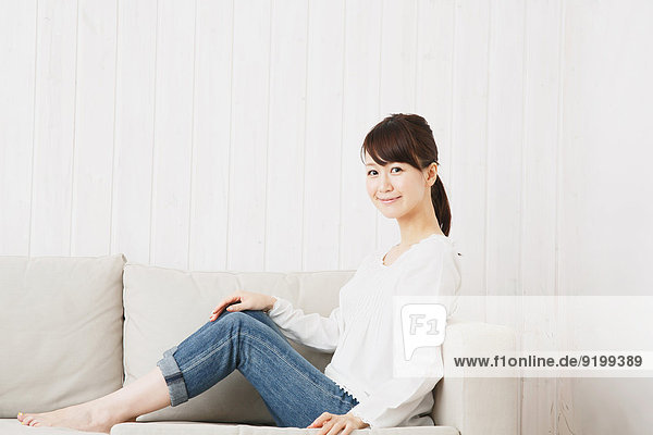 Japanese young woman in jeans and white shirt on the sofa