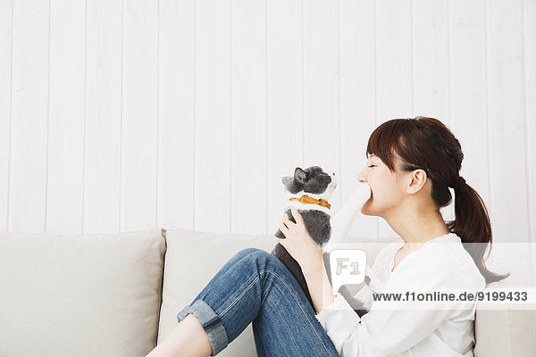 Japanese young woman in jeans and white shirt with cat on the sofa