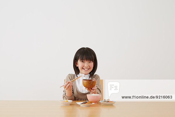 Holztisch jung essen essend isst Mädchen