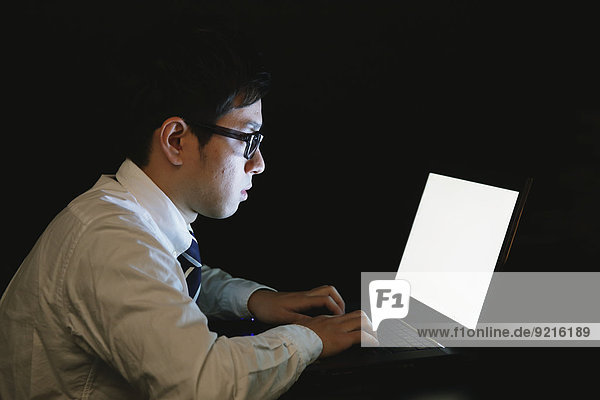 Japanese young businessman working late at his laptop
