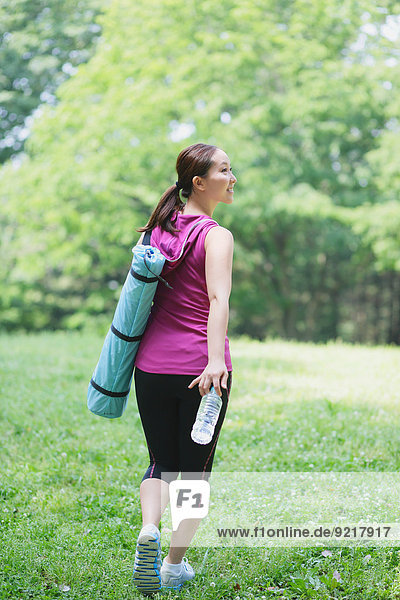 Young Japanese girl with water bottle after training in the park
