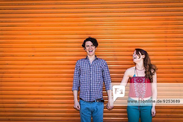 Portrait of couple in front of orange shutter