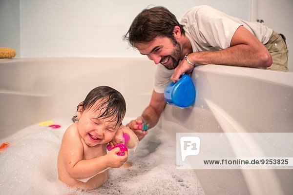 Father and toddler daughter playing at bath time