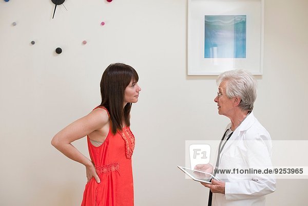 Mature woman questioning female doctor face to face in doctors office