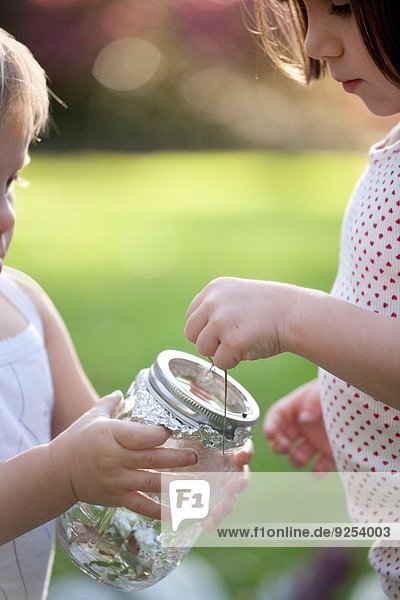 Mädchen und Kleinkind Schwester  die grüne Anole Eidechse in ein Glas legt