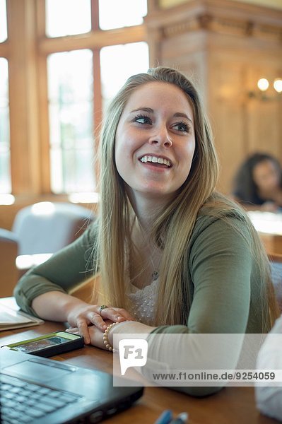 Portrait einer jungen Frau mit Laptop  lächelnd