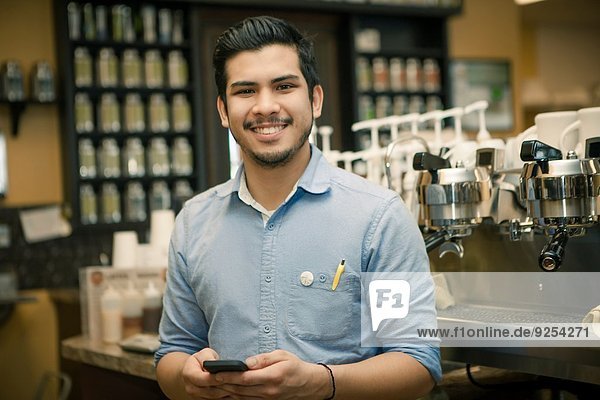 Portrait of barista with smartphone in cafe