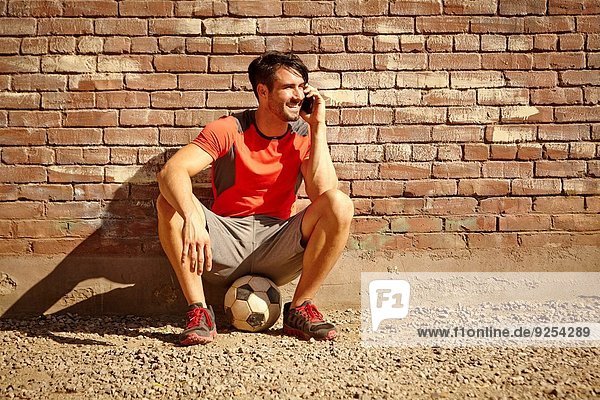 Junge männliche Fußballspieler chatten auf dem Smartphone