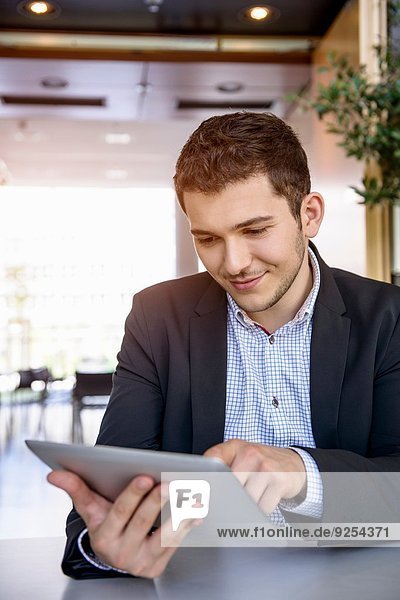 Junger Mann im Büro mit Touchscreen auf digitalem Tablett