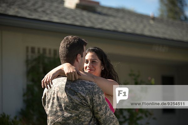 Männlicher Soldat umarmt Frau im Garten beim Homecoming